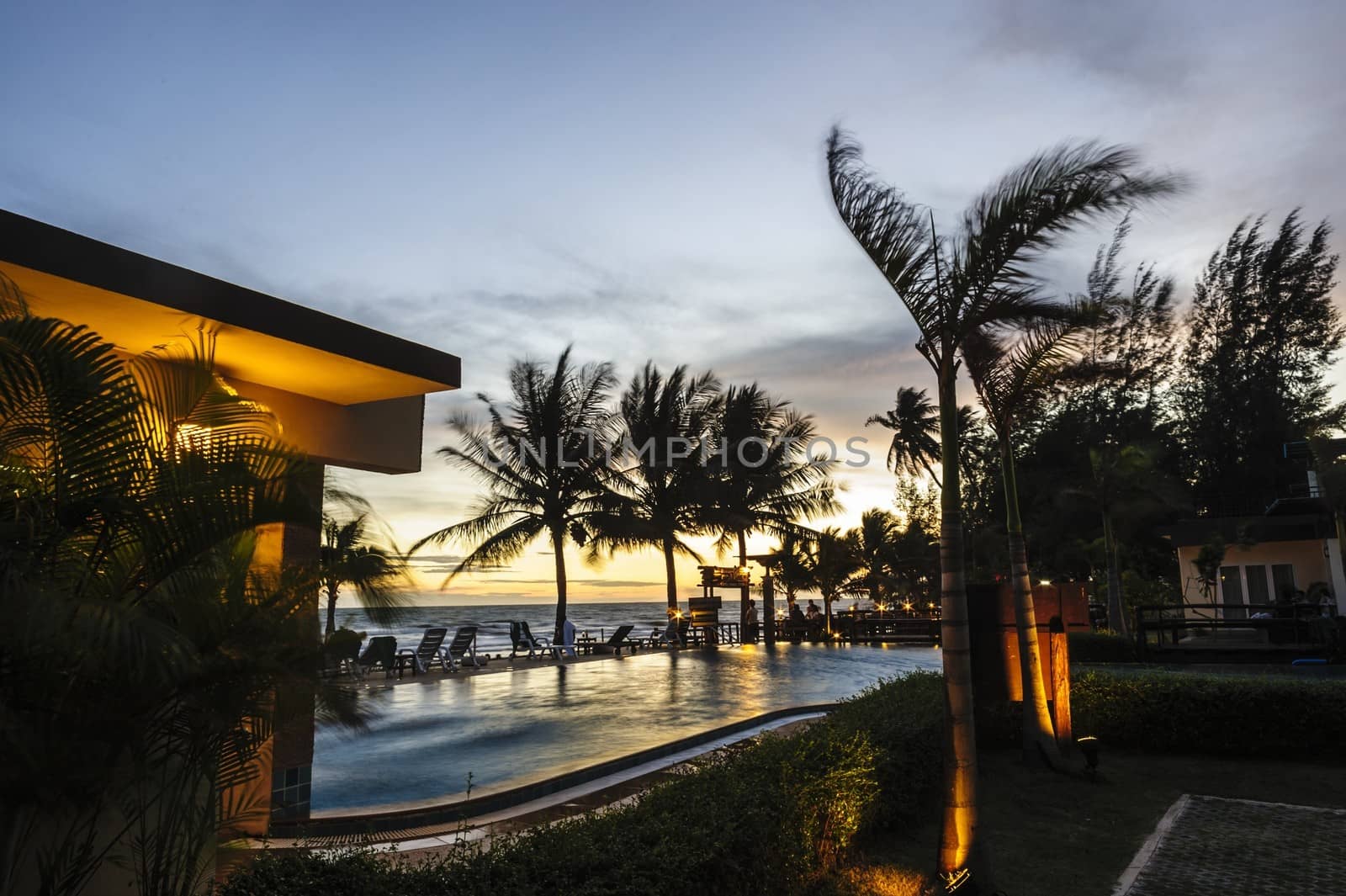 Sunset over  hotel pool on the sea shore in Thailand.