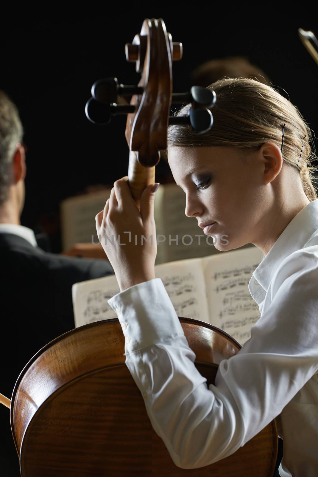 Young beautiful woman playing cello in orchestra