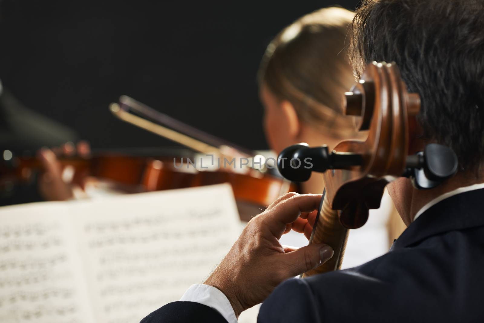 Symphony, cellist on foreground playing at the concert