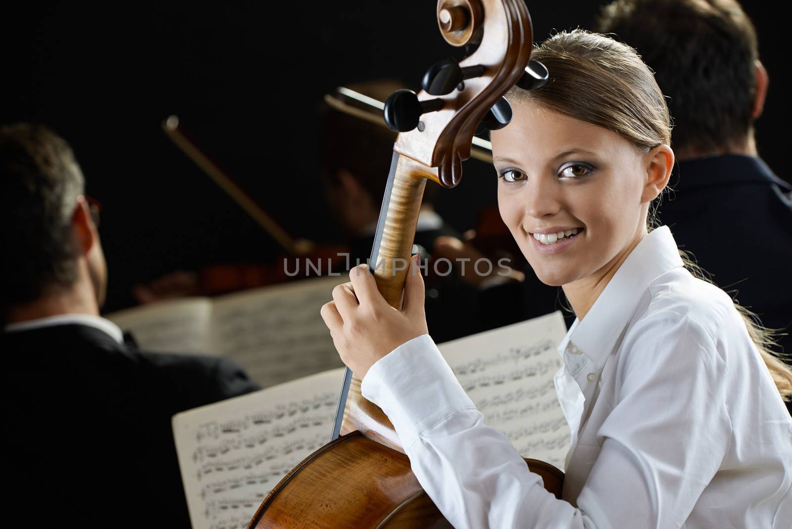 Young beautiful woman playing cello in orchestra