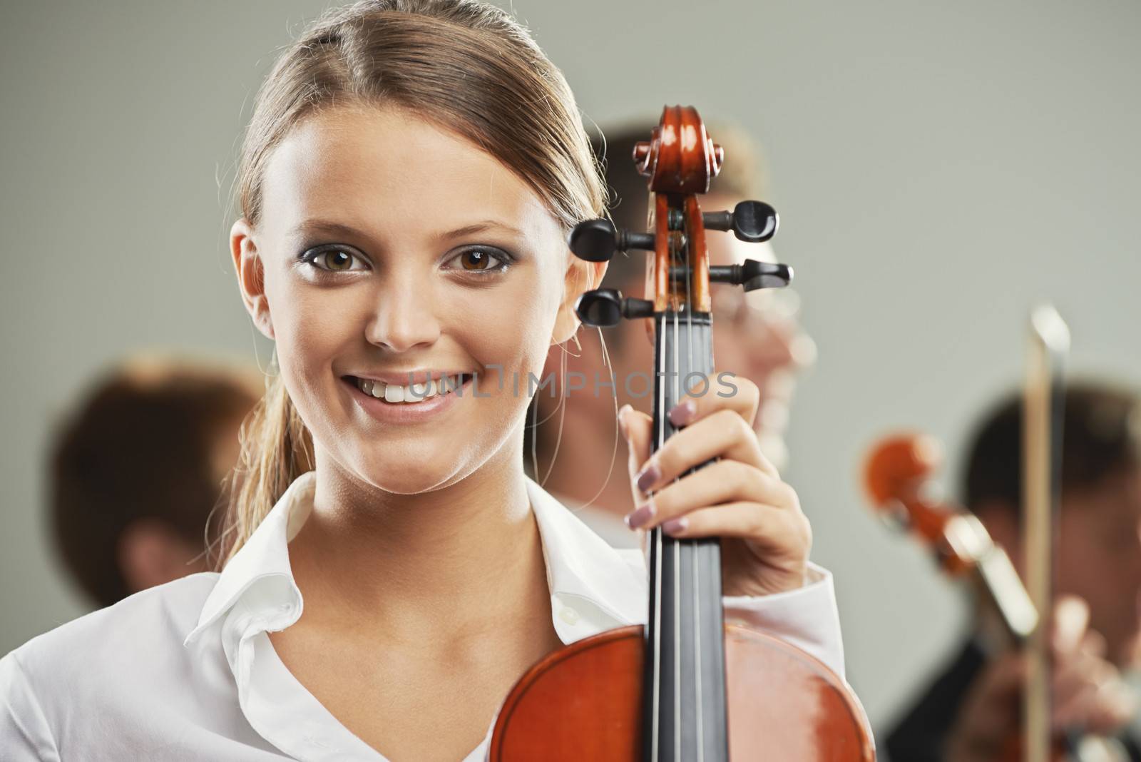 Portrait of a beautiful female violinist, musicians on background