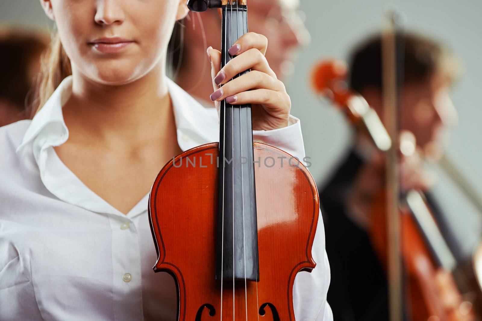 Close up portrait of a female violinist, musicians on background