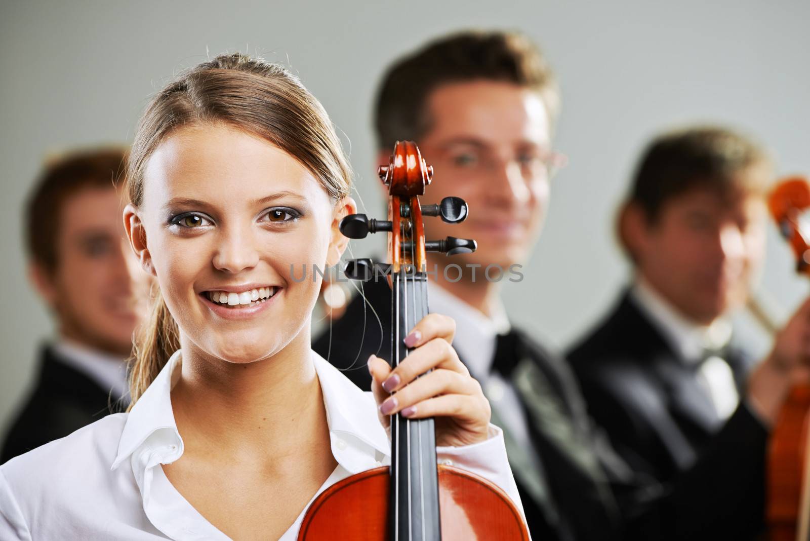 Portrait of a beautiful female violinist, musicians on background