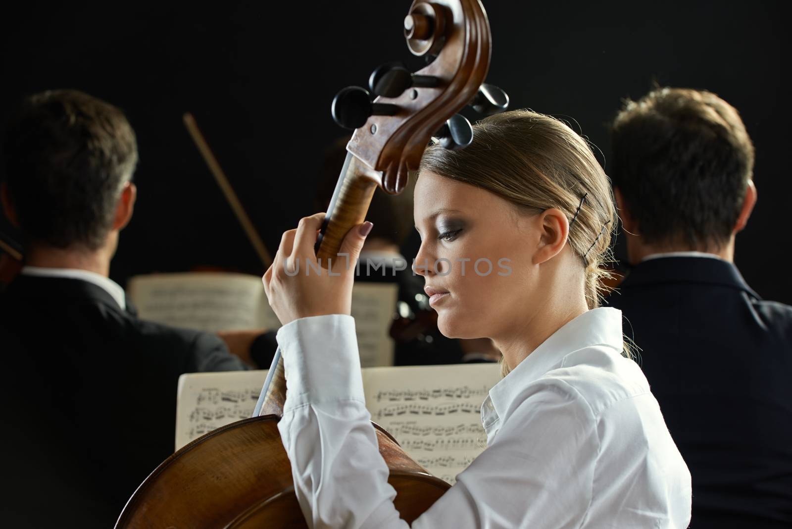 Young beautiful woman playing cello in orchestra