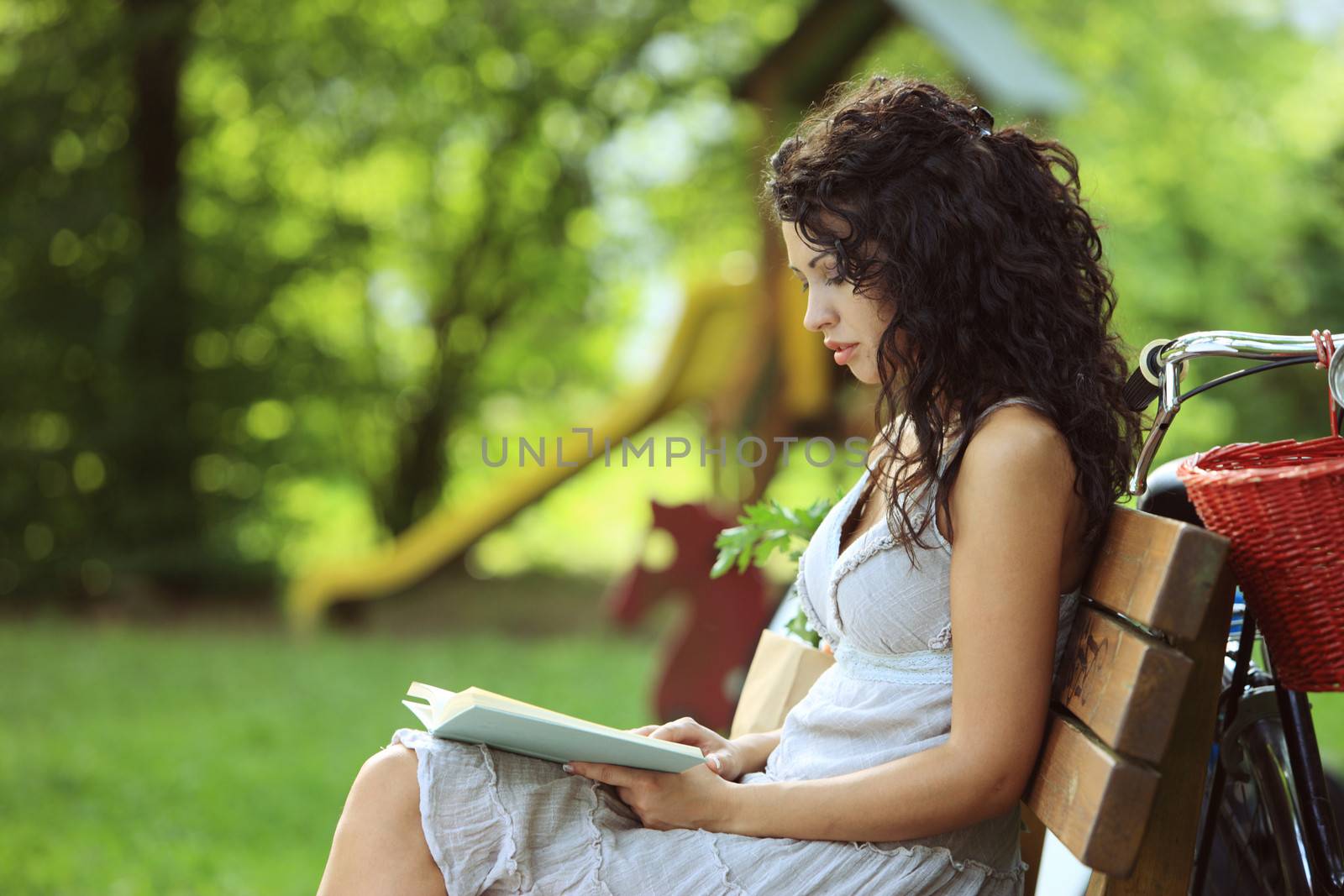 Young beautiful woman reading a book at a park