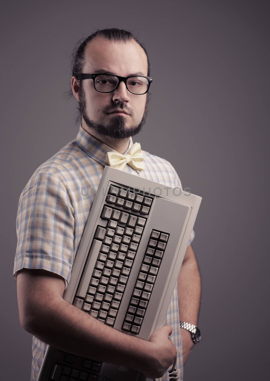 Funny guy posing with a keyboard on grey background