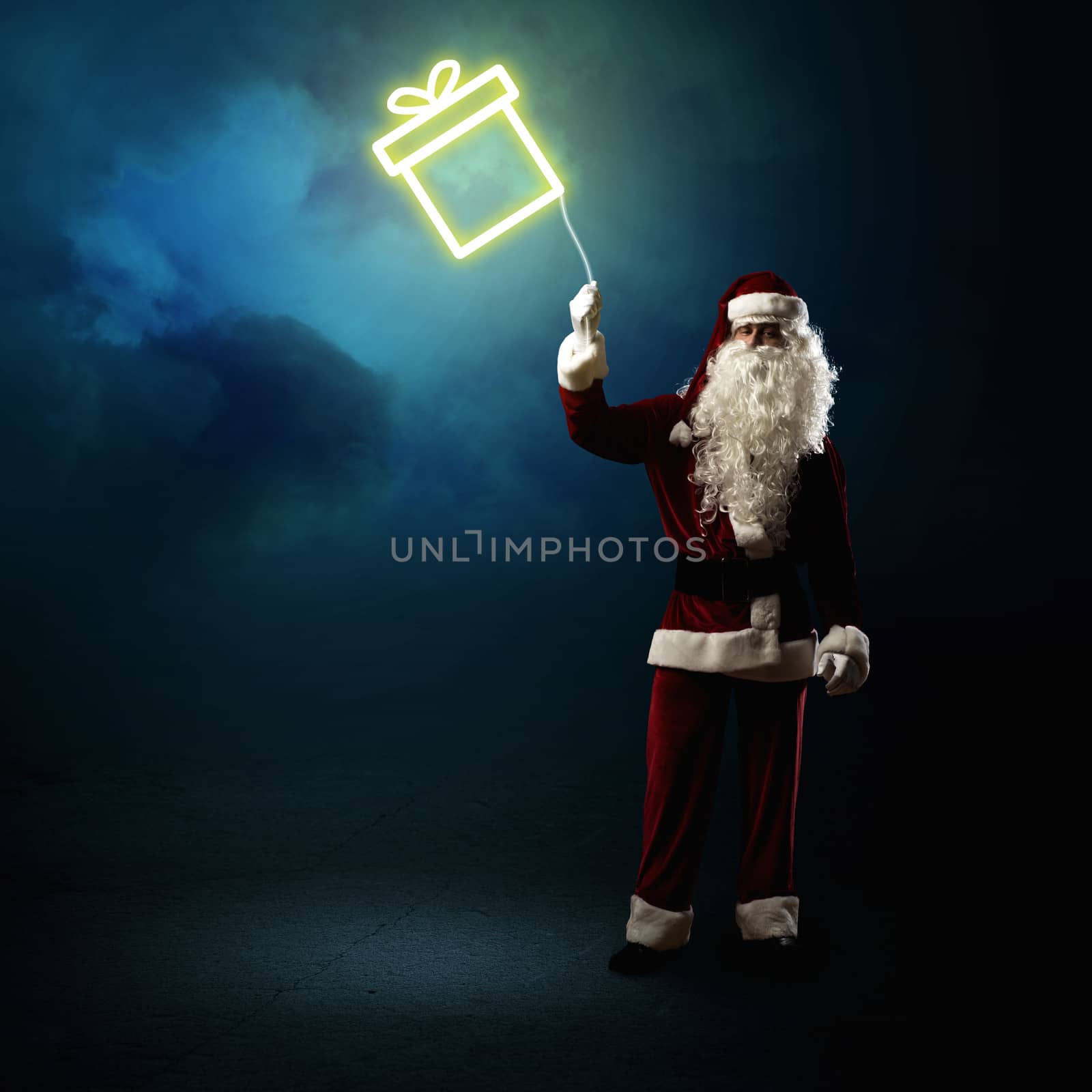 Santa Claus is holding a shining symbol of the gift on a string