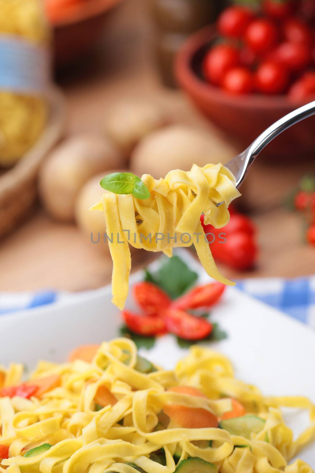 Fork holds tagliatelle with some basil leaves 