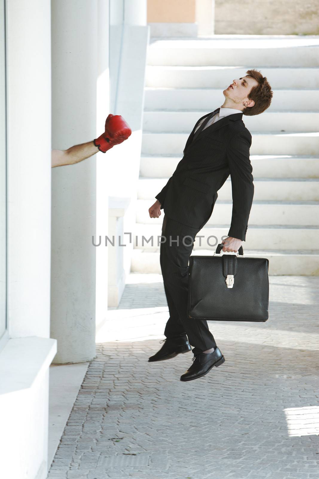 Young businessman gets knocked out by a punch, business failure concept