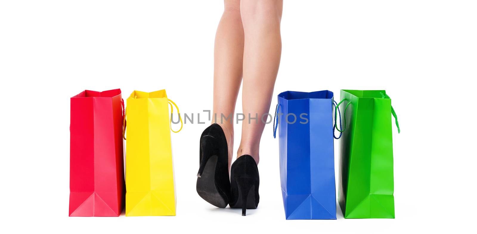 closeup of beautiful legs and colorful shopping bags aside