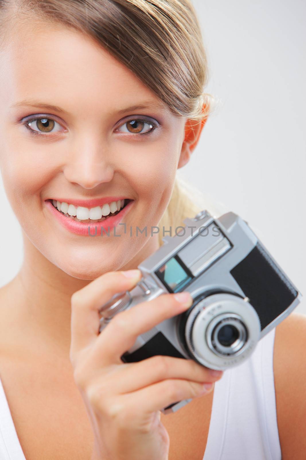 Portrait of a beautiful girl holding a vintage camera and smiling