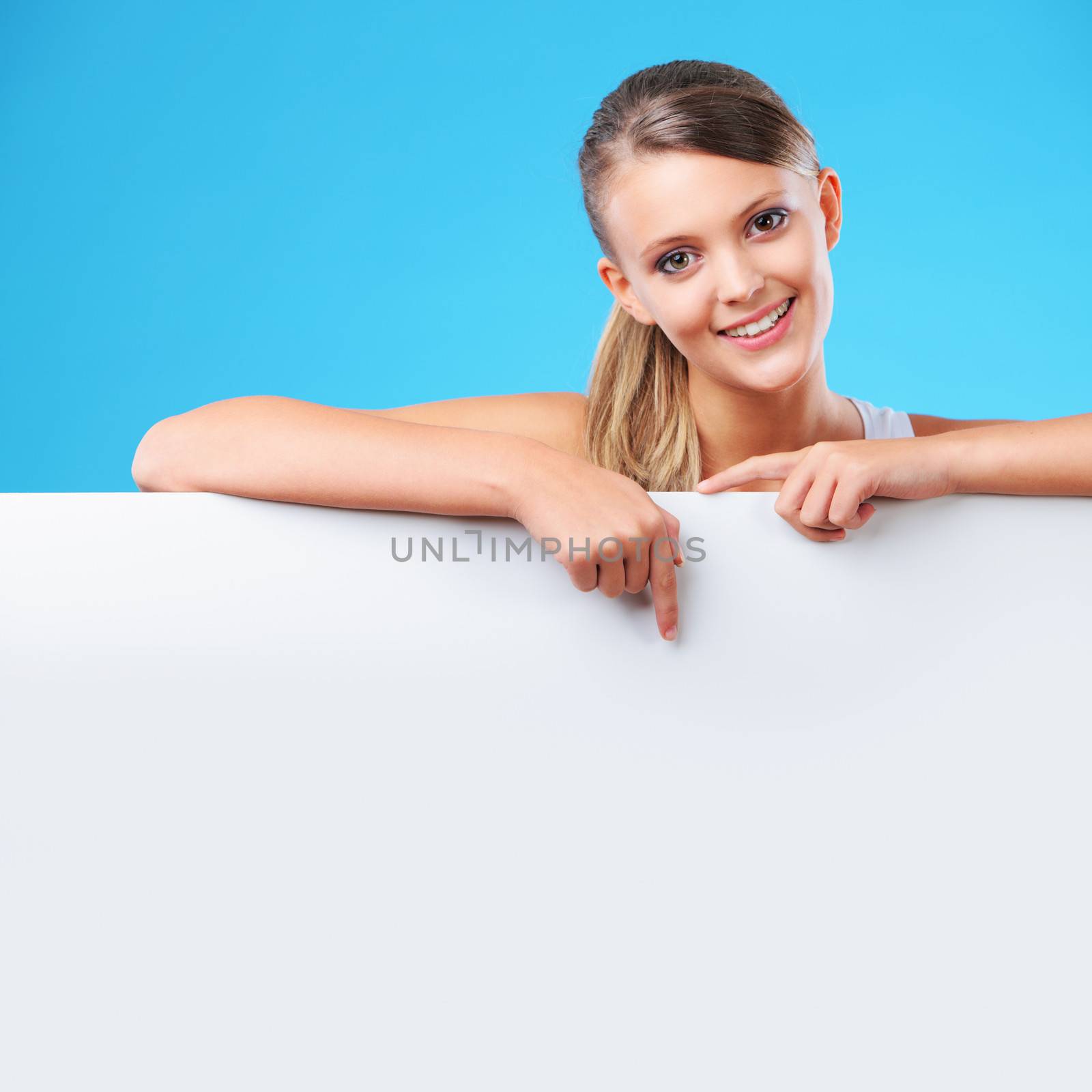 Beautiful young woman pointing at copyspace 