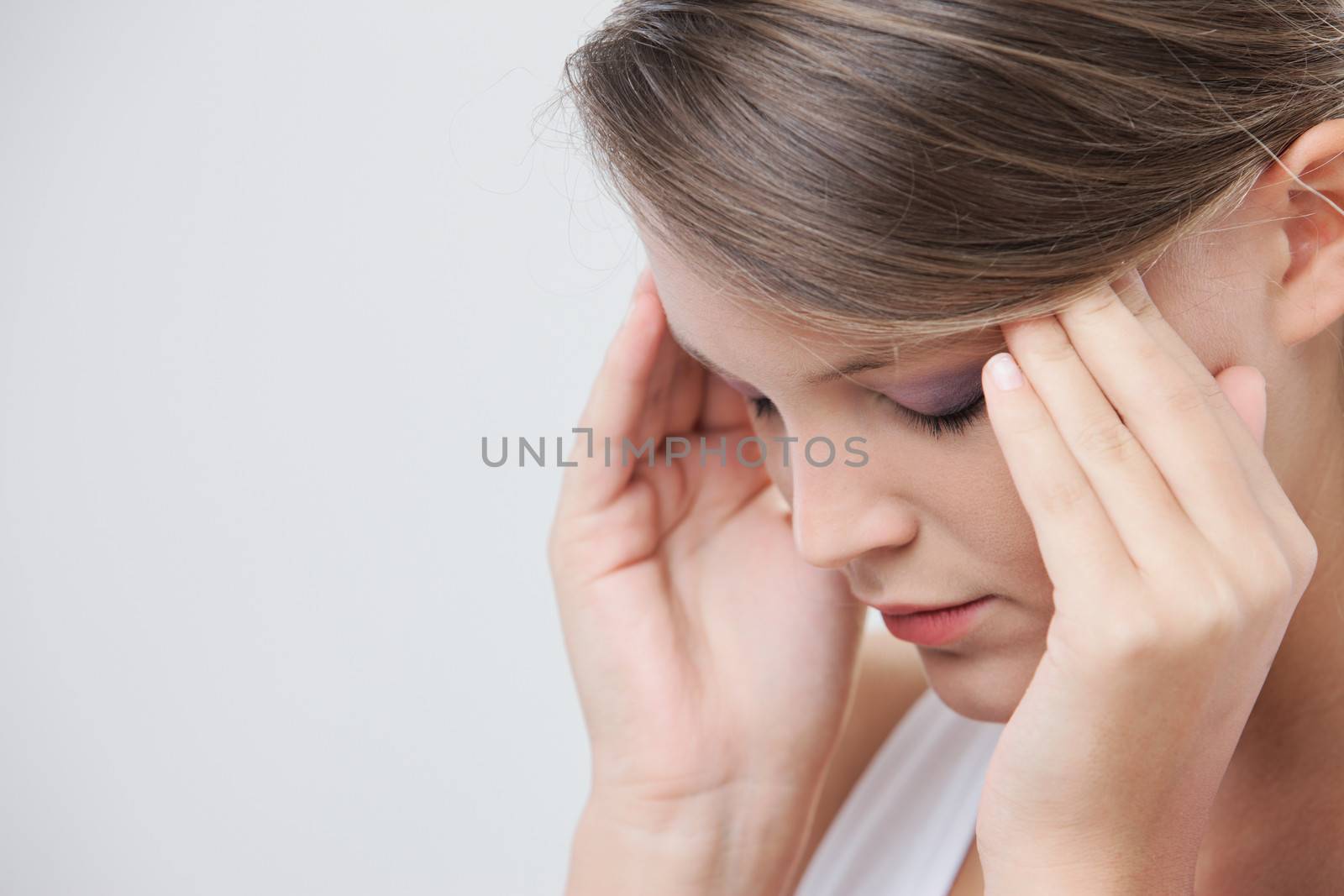 Close up headshot of a beauty rubbing at her temples to relieve a headache