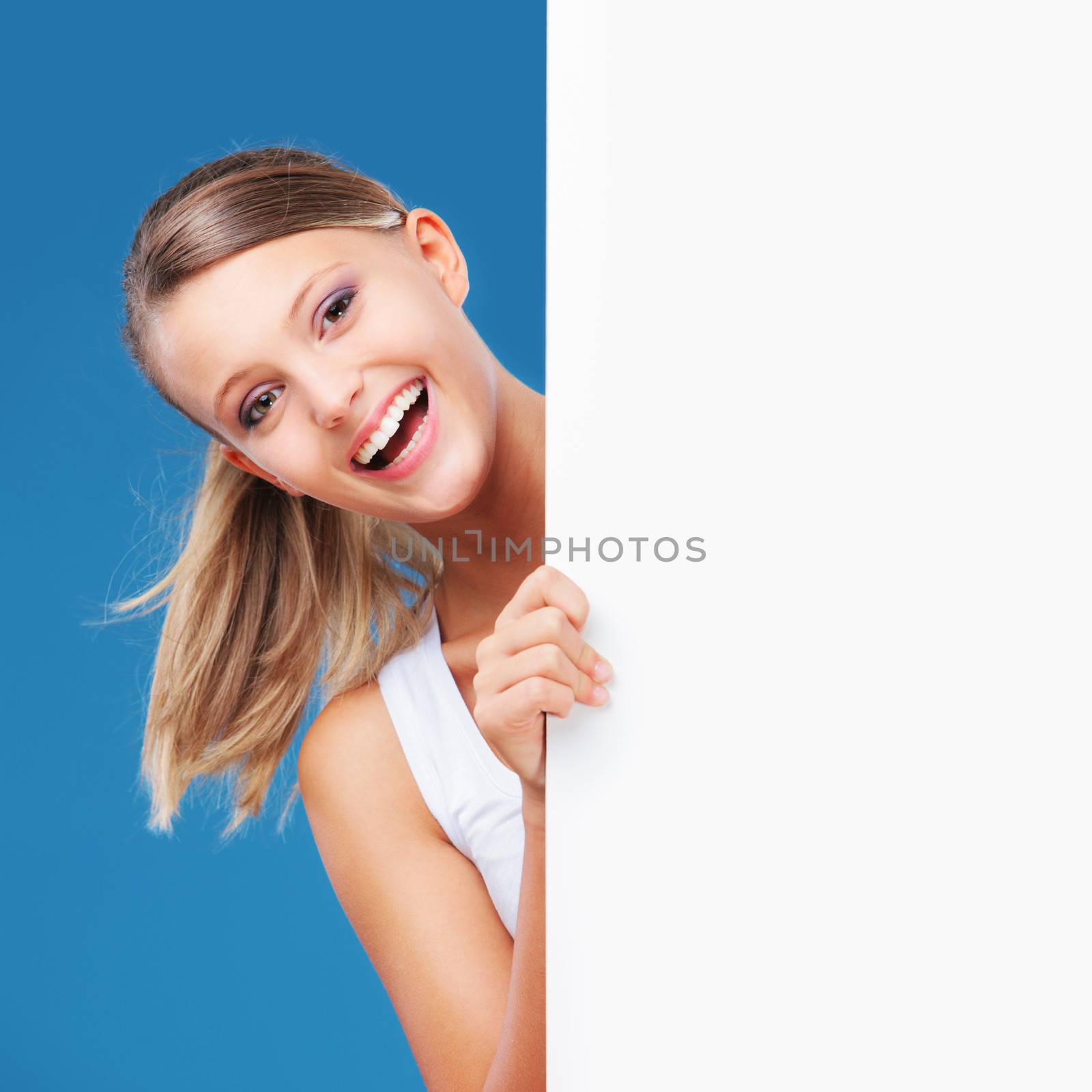 Happy girl looking at the camera from behind a large blank placard