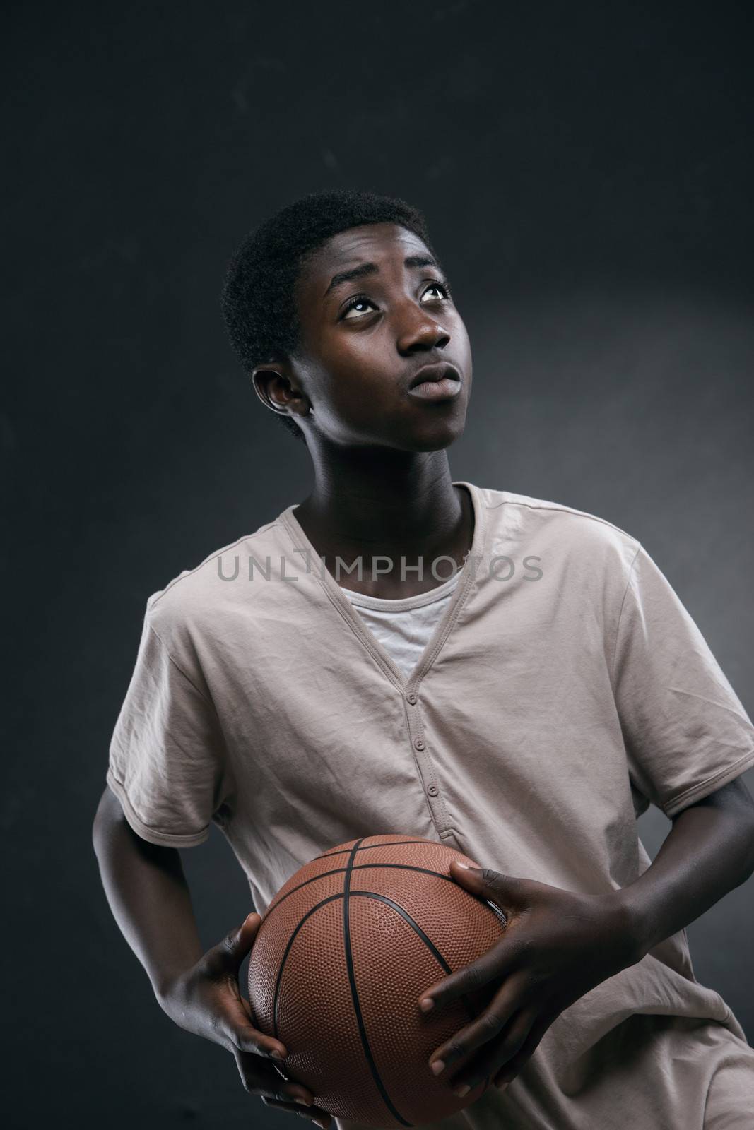 An African boy playing basketball on dark background
