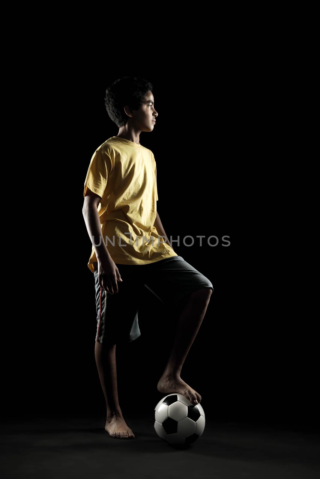 Portrait of young boy with a soccer ball on black background