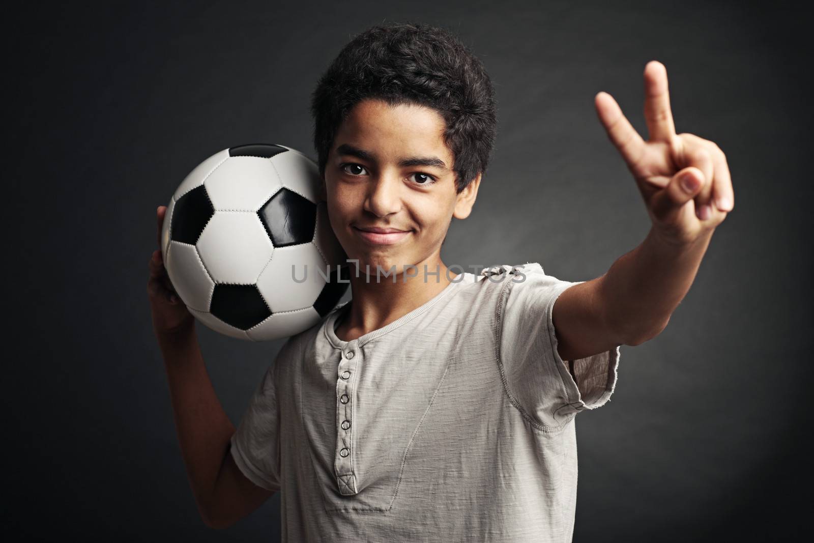 Portrait of young boy with a soccer ball signing victory