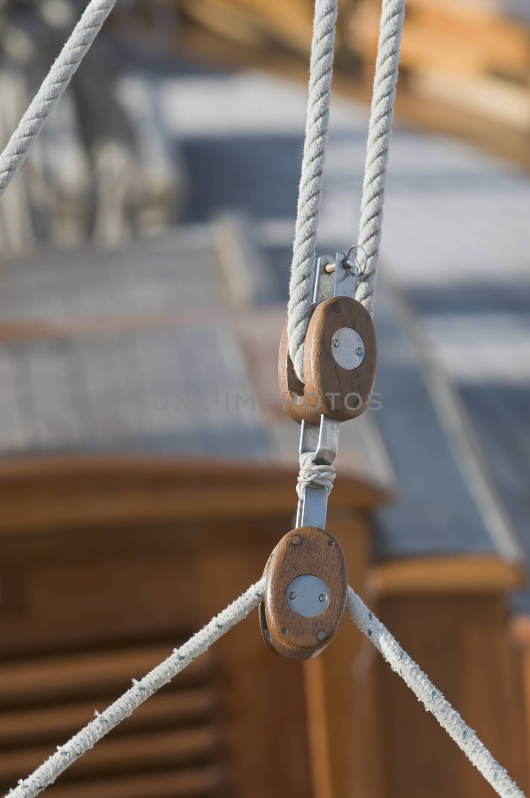 Detail of a wooden yacht: ropes and blocks with deck in background