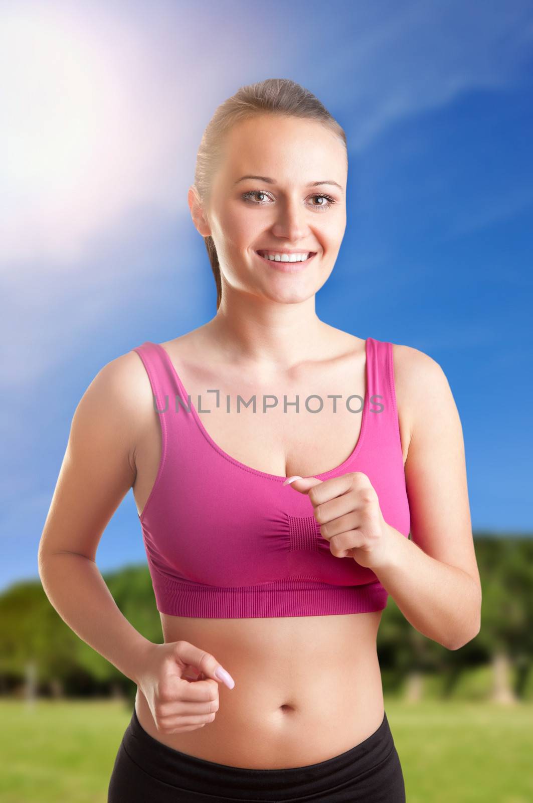 Young fit woman jogging in a park with a sun flare behind her