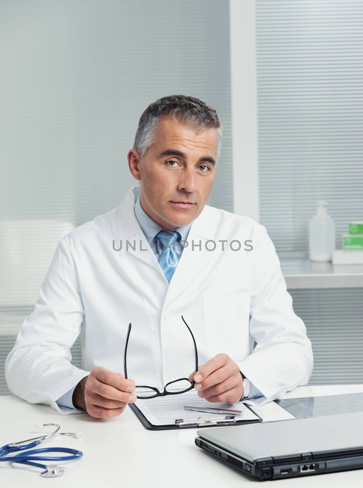 Mature male doctor sitting at desk in doctor's room