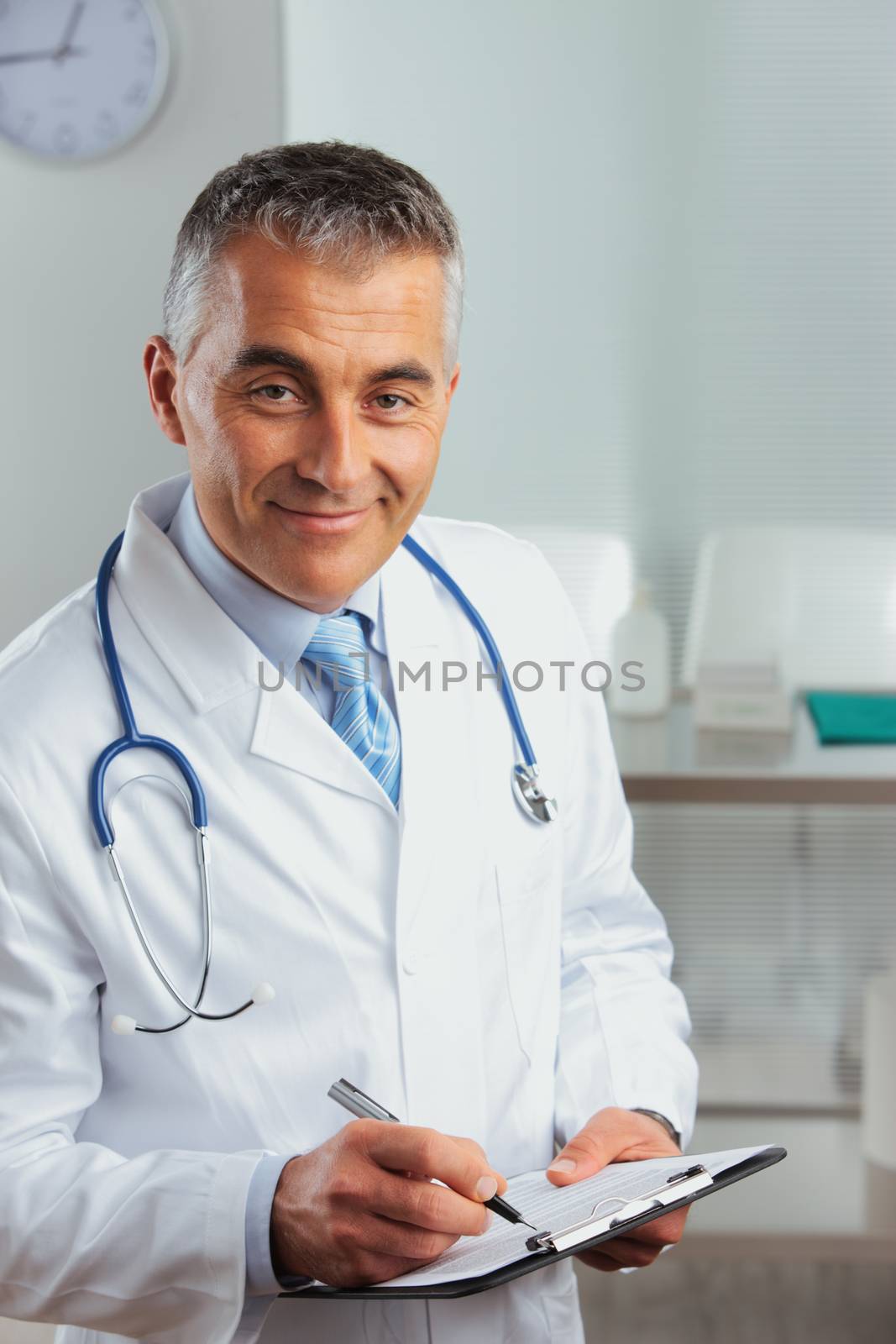 Portrait of a doctor writing on clipboard and smiling at the camera 