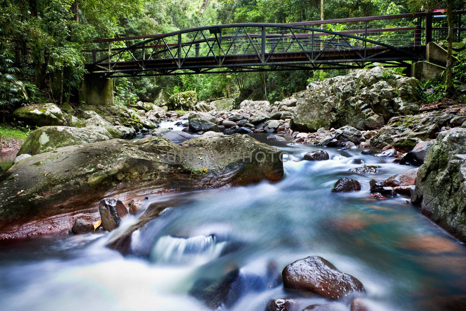 Water flowing under a bridge by jrstock