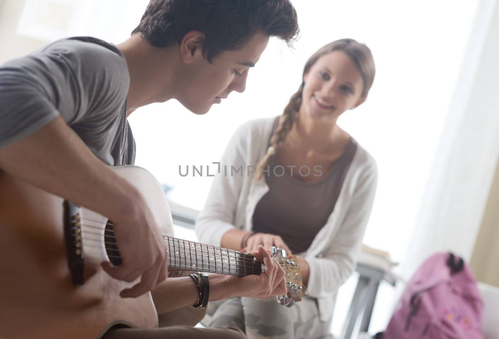 Young handsome man playing guitar for his girlfriend