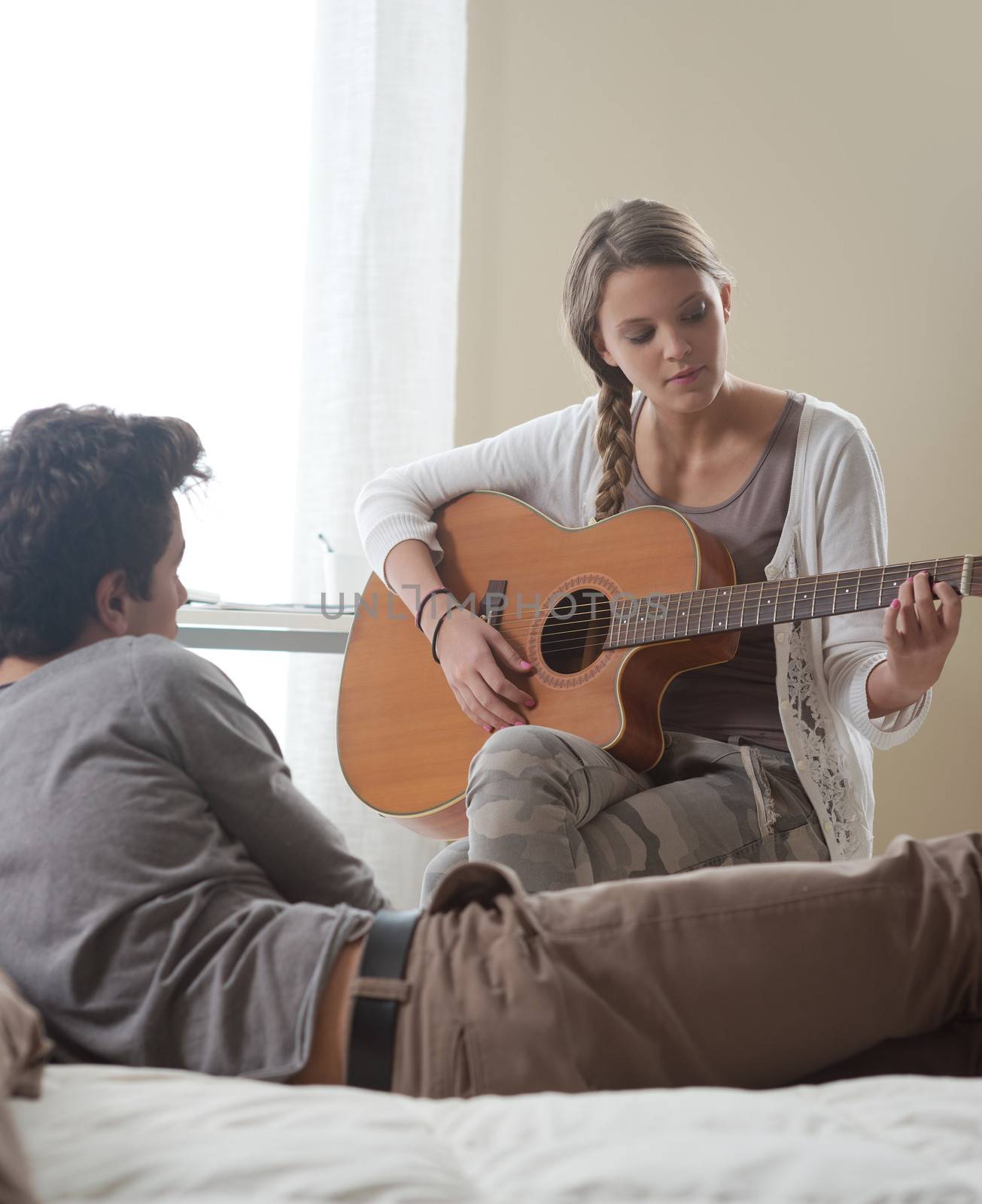 Beautiful girl playing guitar for her boyfriend at home 