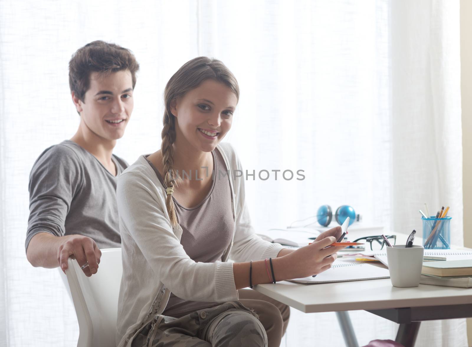 Portrait of two young smiling students at home