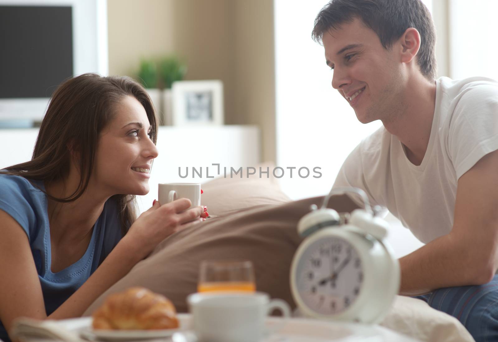 Beautiful smiling young couple having breakfast in bed