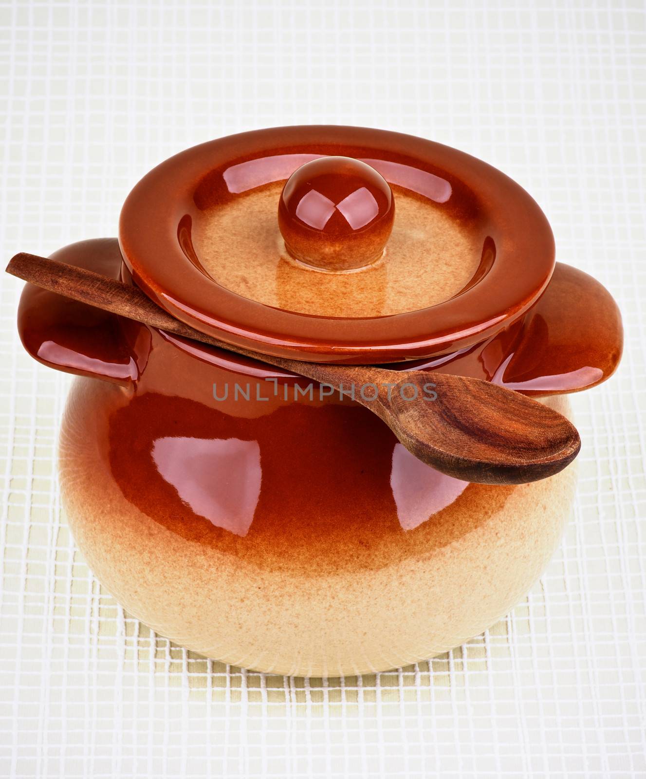 Brownish Stoneware Pot and Wooden Spoon under Lid isolated on Light Green Checkered background