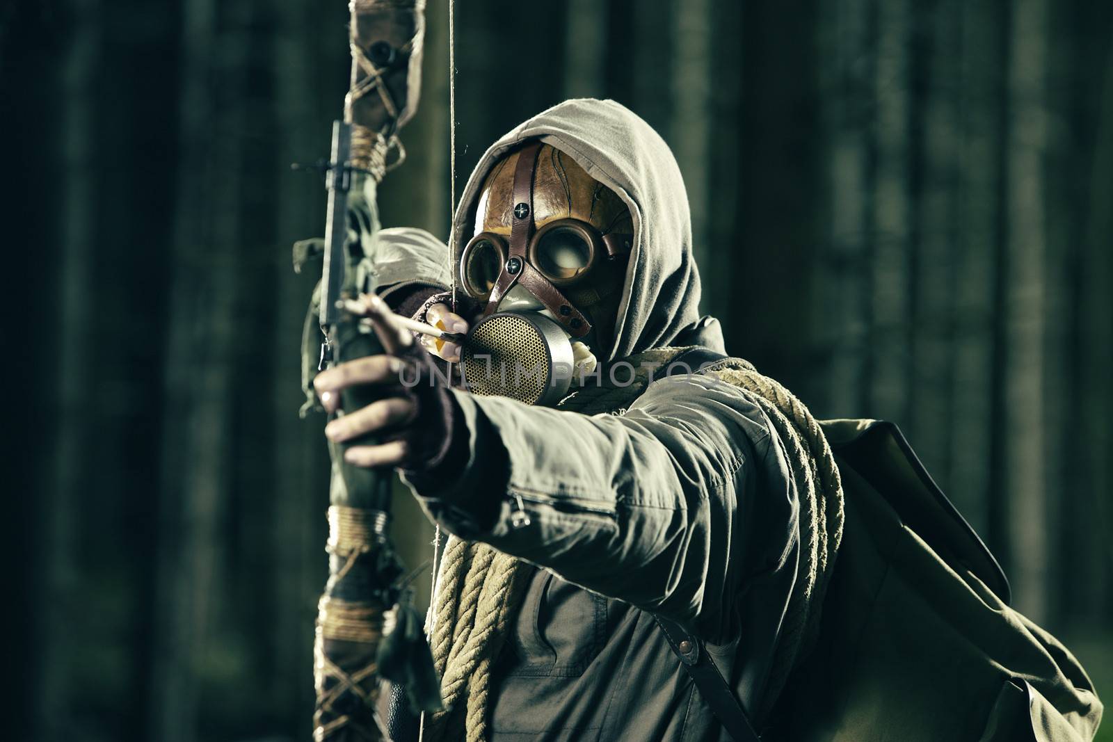 A male bow hunter wearing gas mask by stokkete