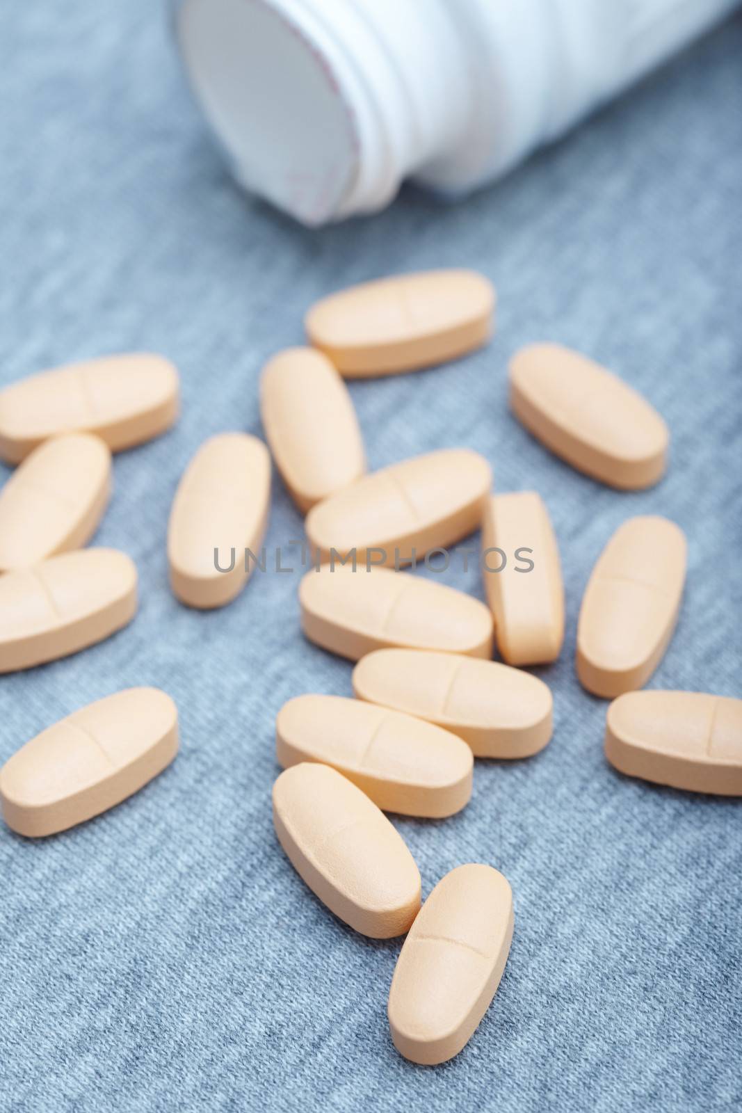 Many pills near white container. Close-up photo