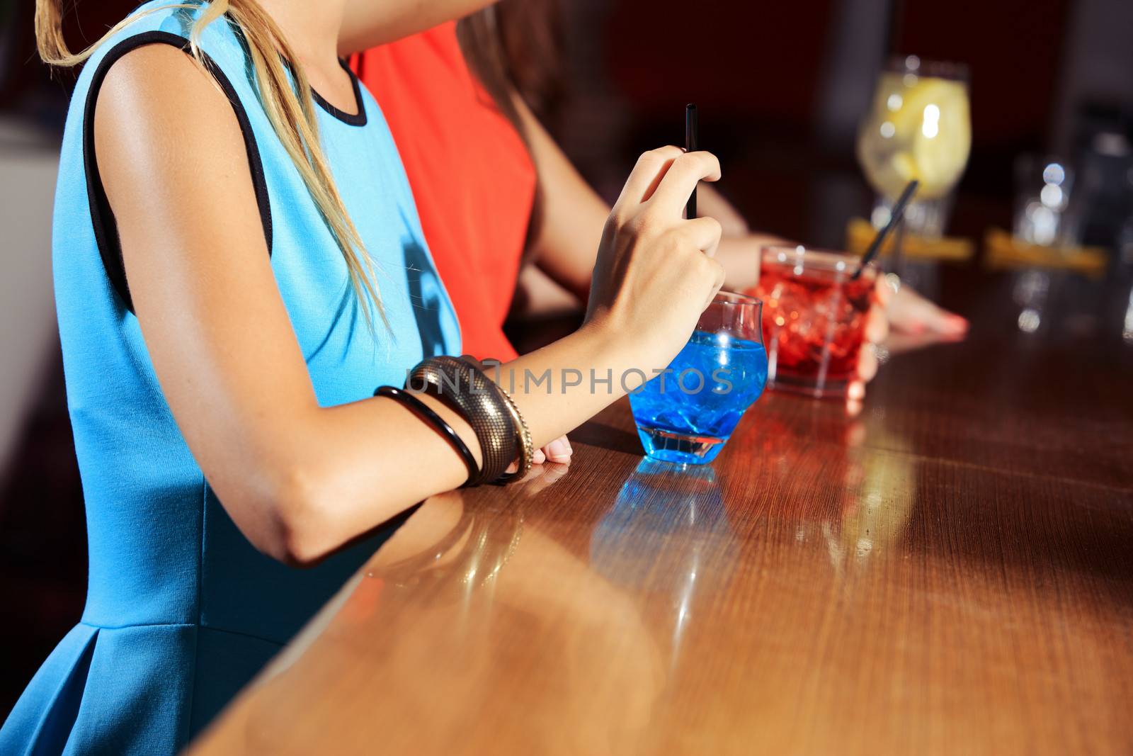 Drinking a blue cocktail at nightclub, hands close up