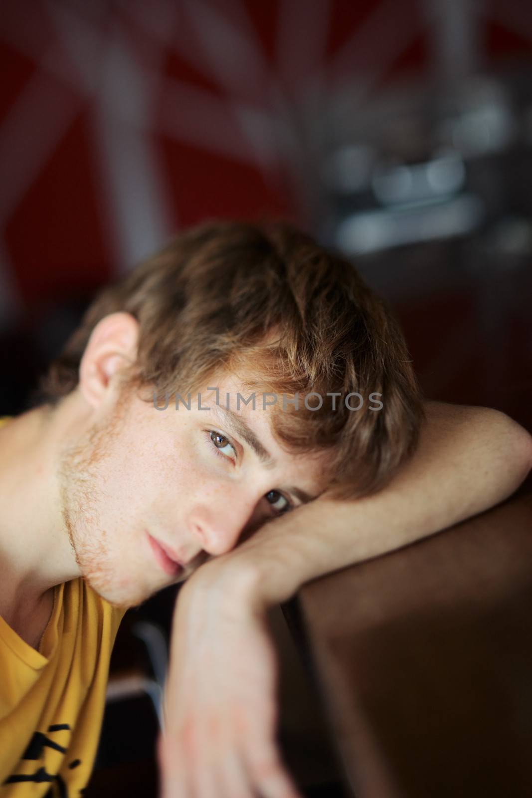 Portrait of a tired young man leaning on the bar table.Tilt shift lens