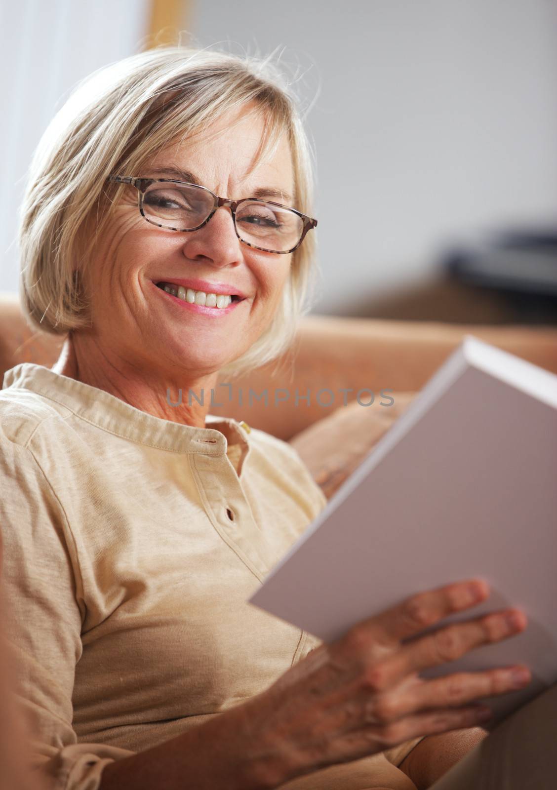 Smiling senior woman reading a book at home