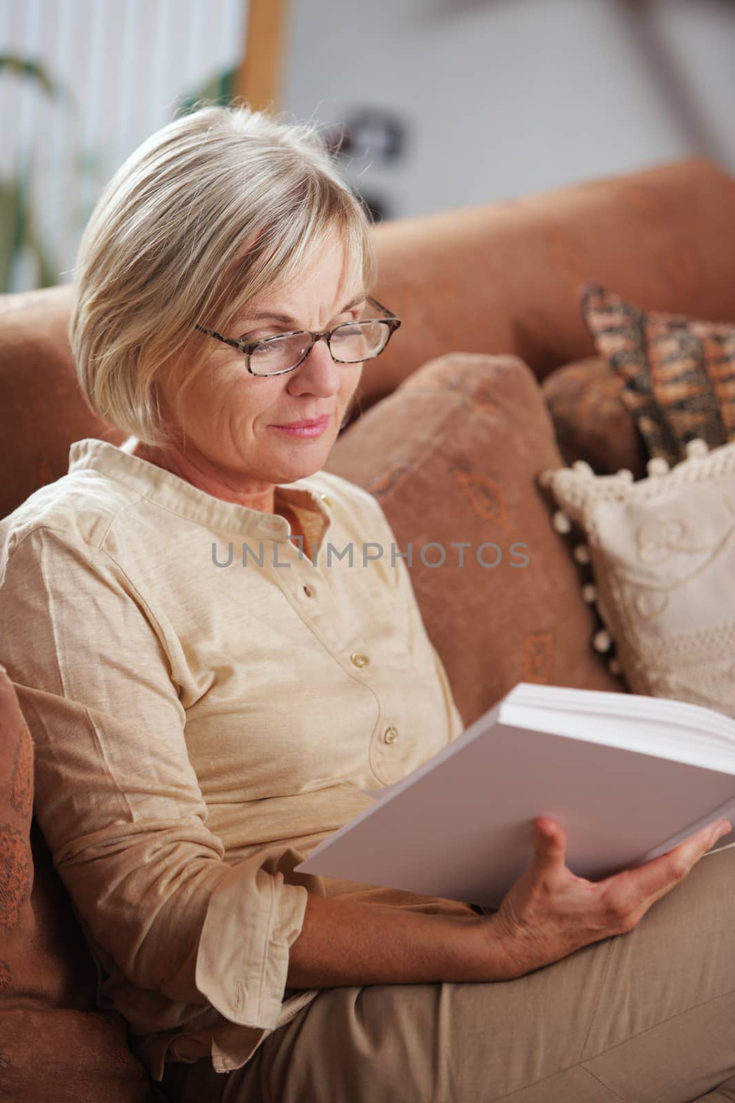 Mature Caucasian woman reading a book at home