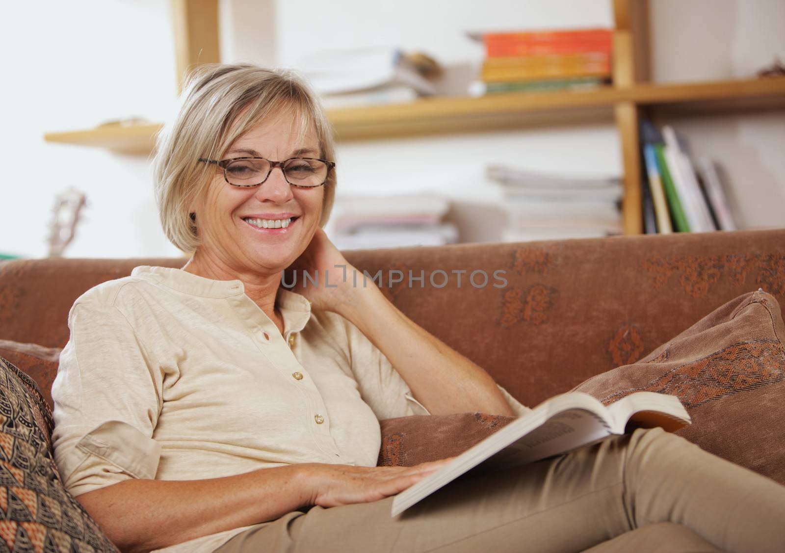 Smiling senior woman reading a book at home