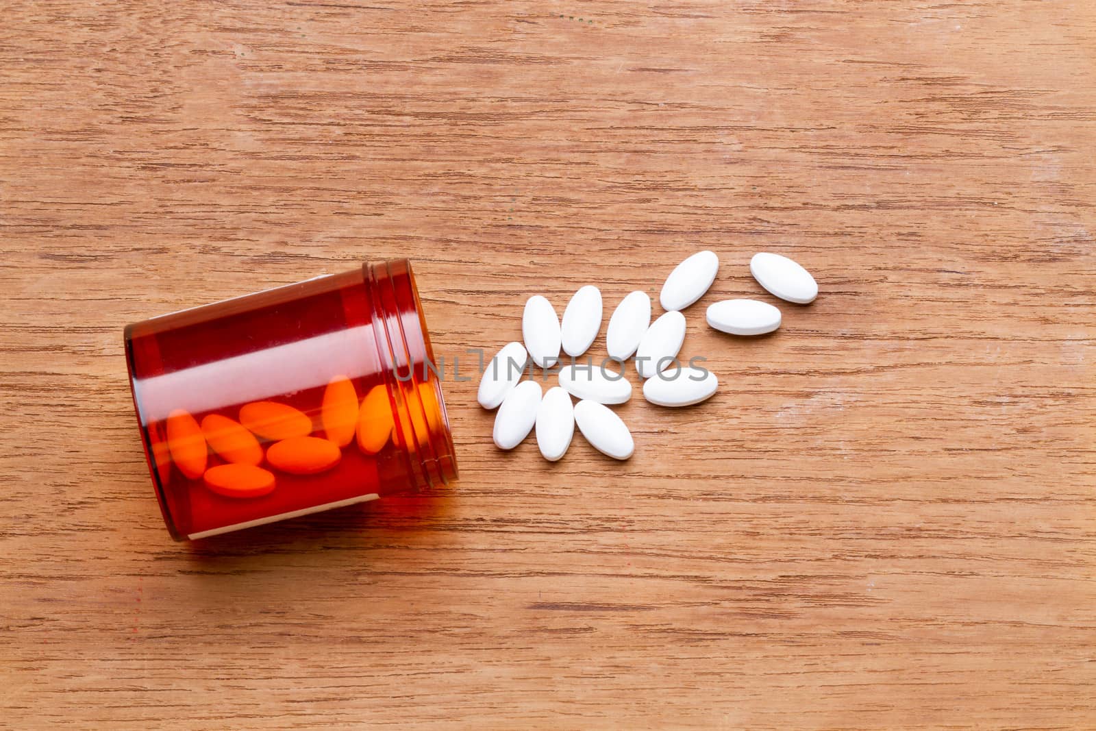 white pill with bottle on wooden plate