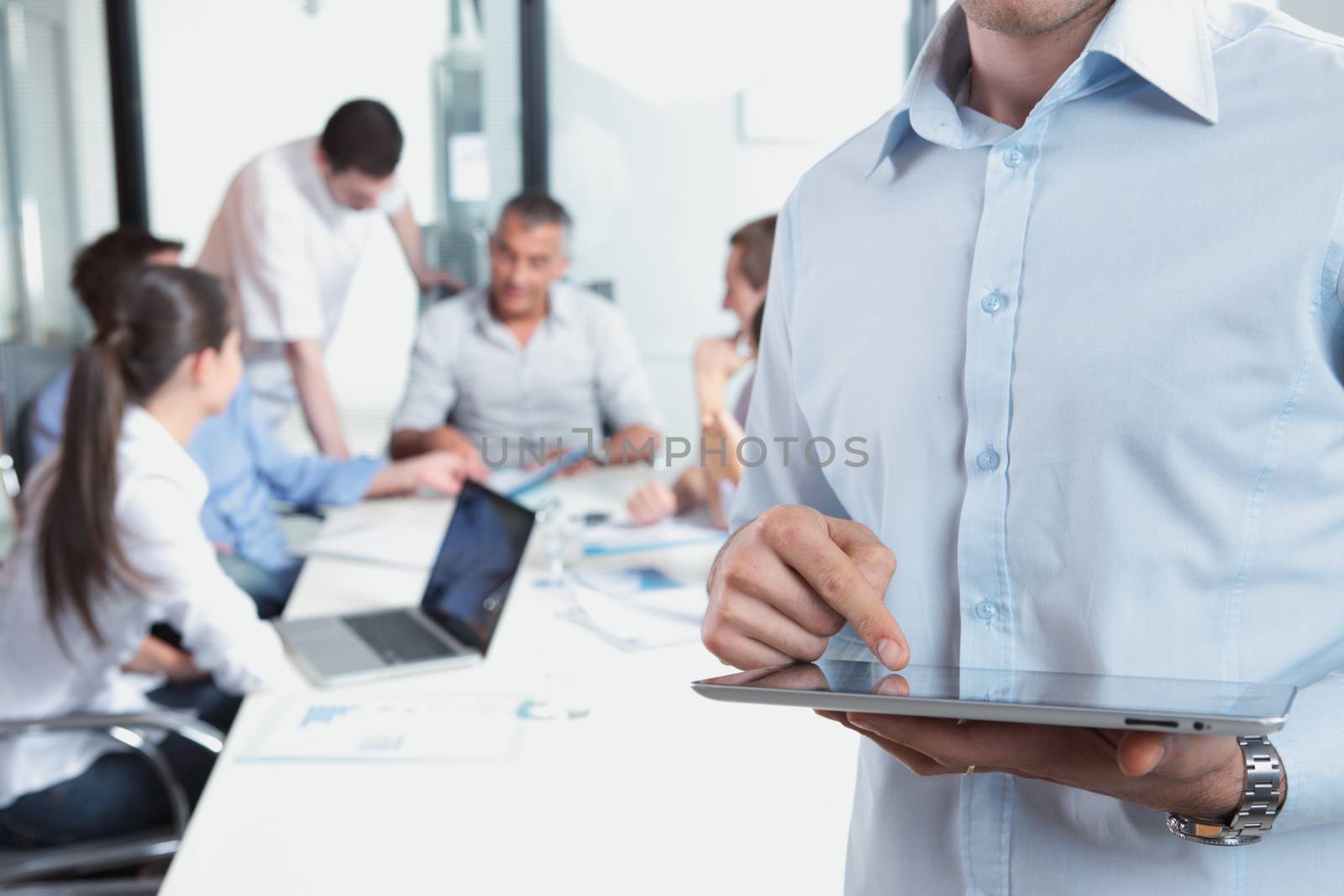 Close up of a business man holding his digital tablet, meeting on background