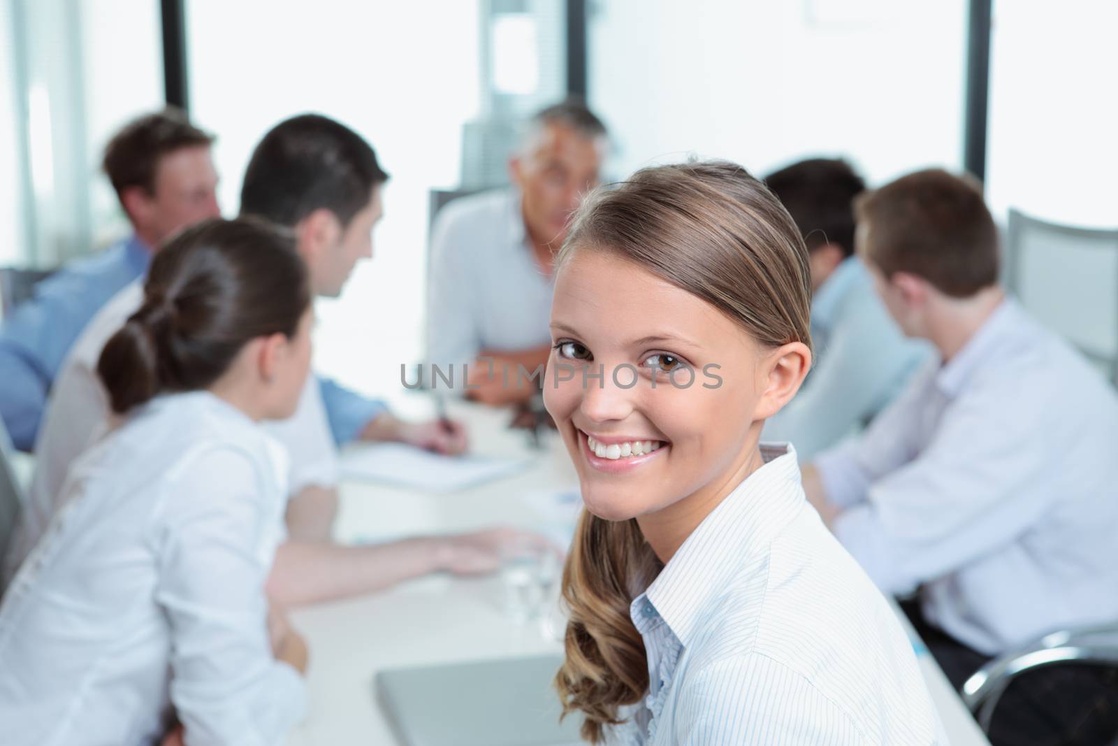 Portrait of a smiling young business woman with her team in the background 