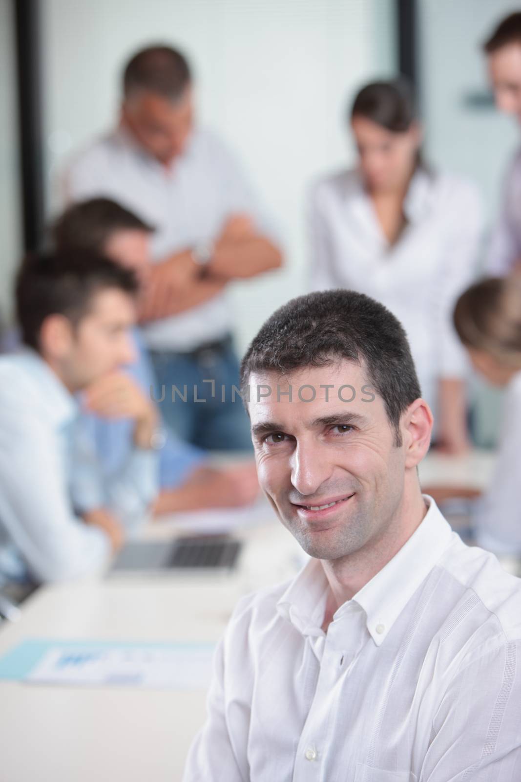 Portrait of a handsome businessman, blurred colleagues in the background 