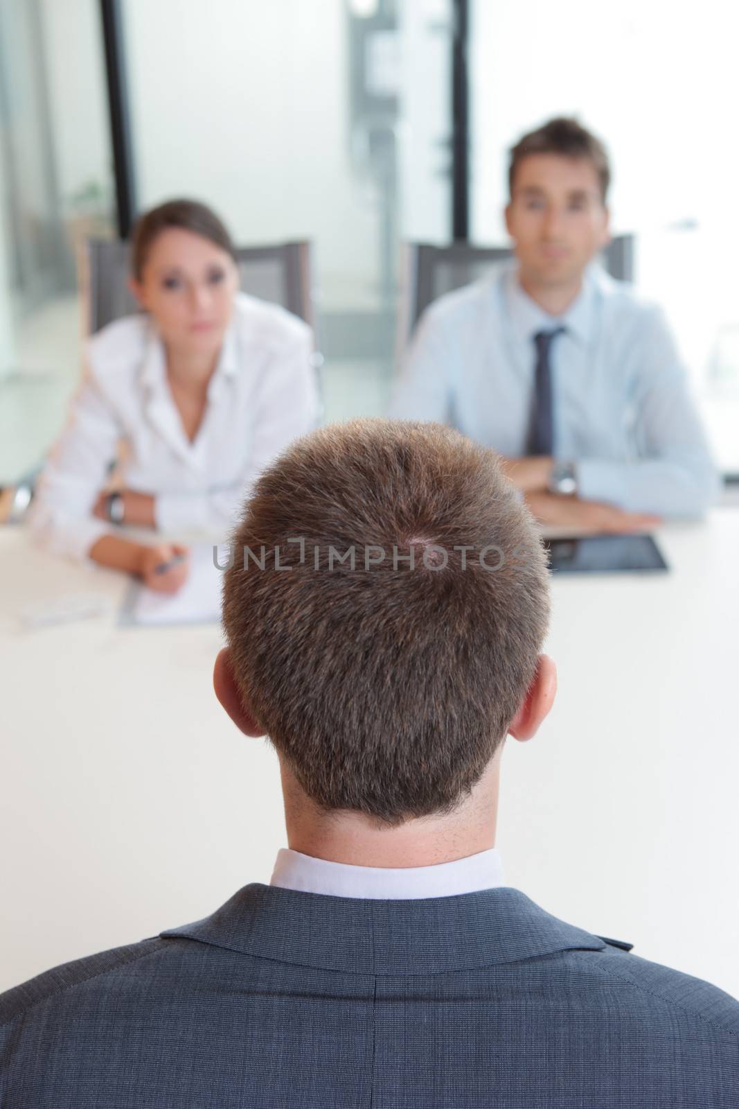 Two business people having job interview with young man