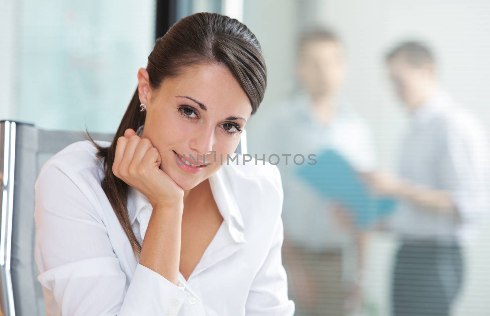 Portrait of a pretty business woman smiling, blurred colleagues in the background 