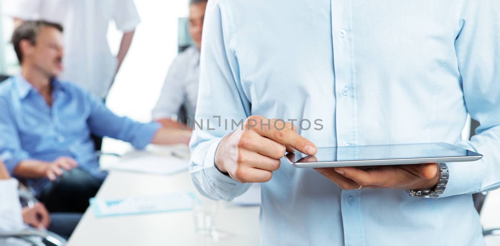 Close up of a business man holding his digital tablet, meeting on background