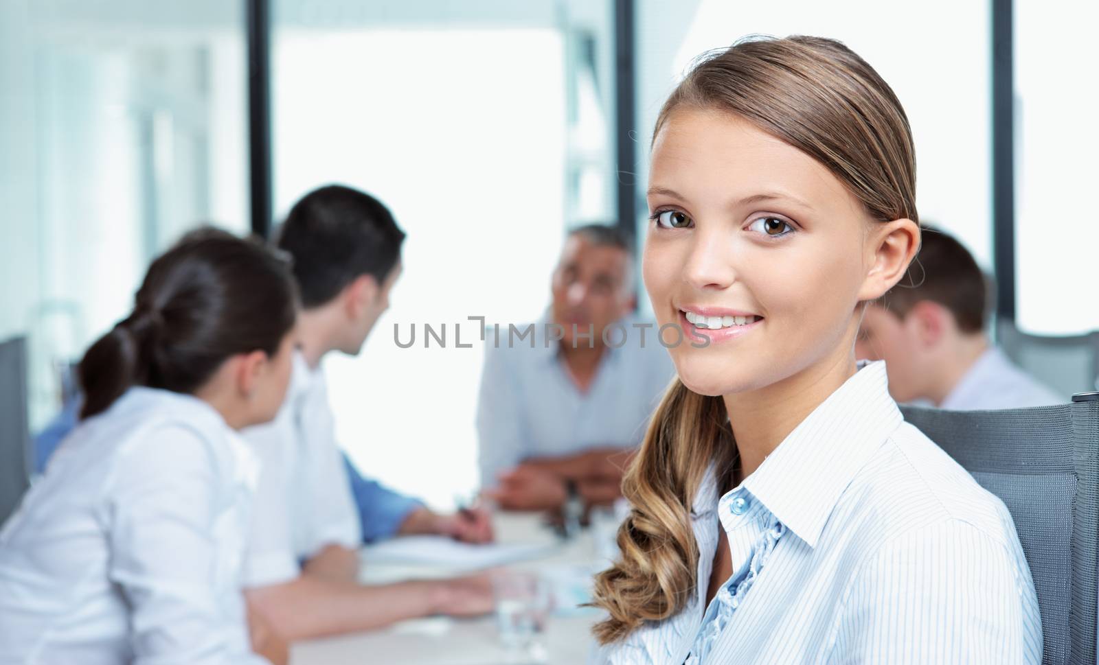 Portrait of a pretty young executive with her team in the background 