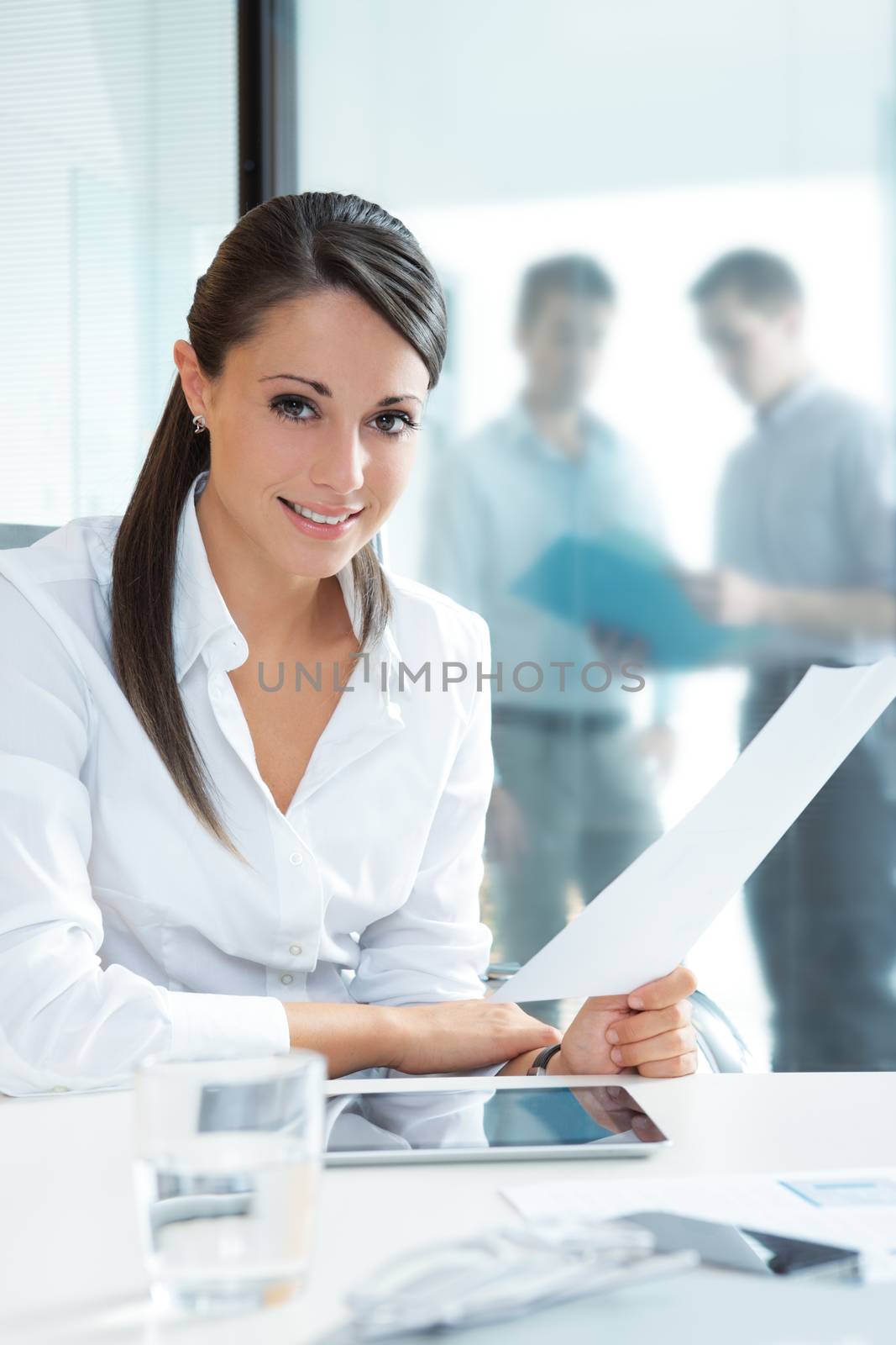 Portrait of a pretty businesswoman smiling, blurred colleagues in the background 