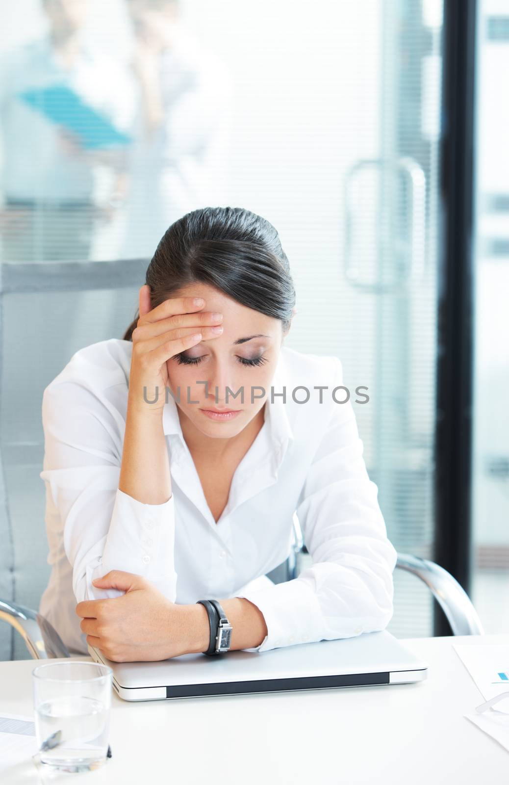 Young tired business woman with headache sitting  in workplace