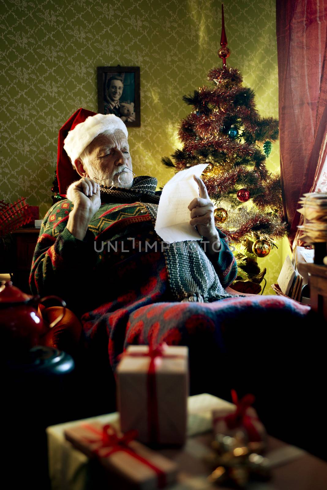 Portrait of Father Christmas sitting in armchair reading letters