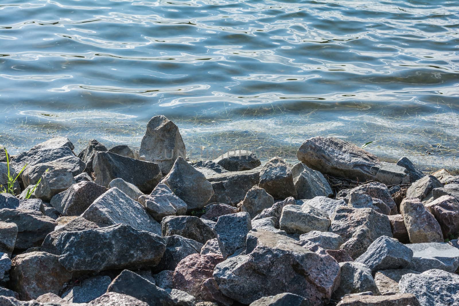 Pile of rocks on lakeside  by IVYPHOTOS